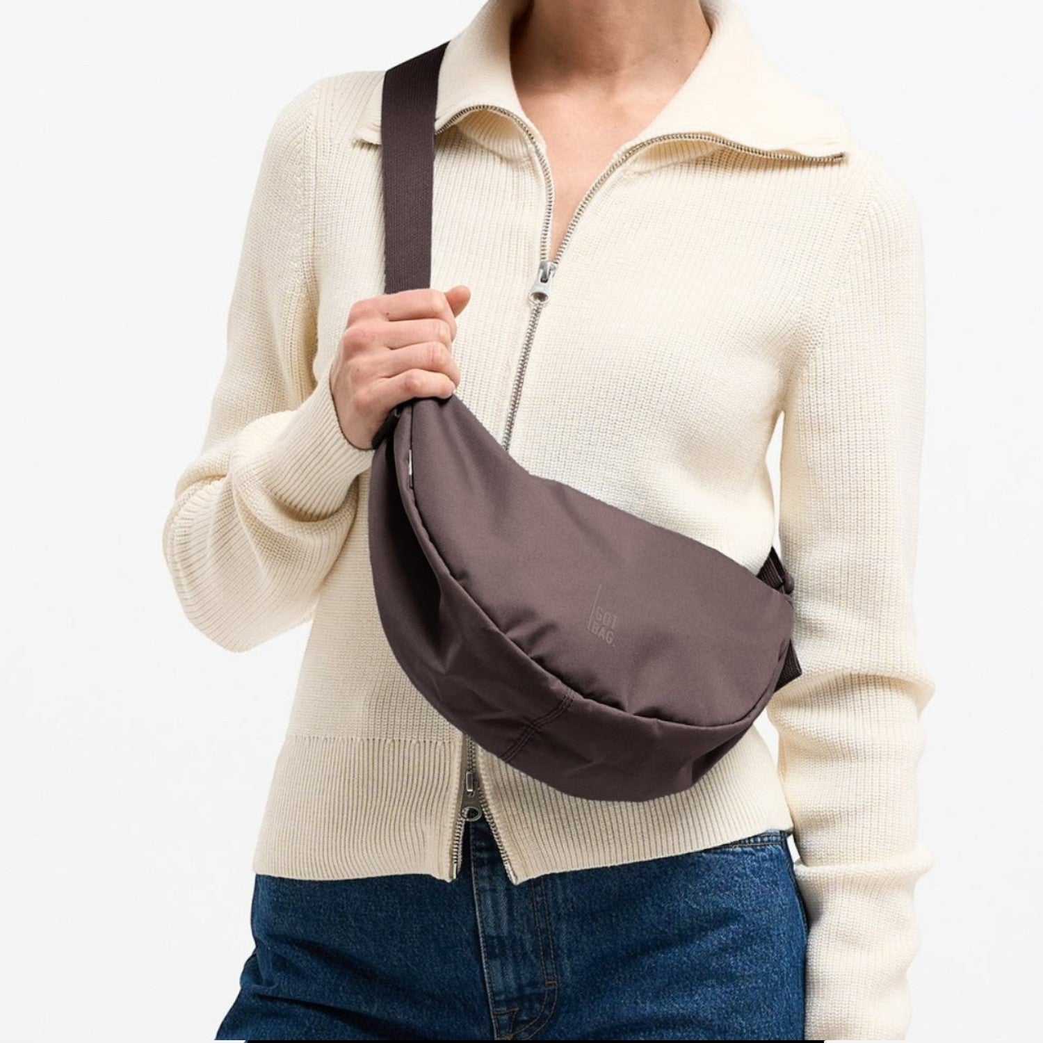 Lieblingstasche Moon Bag Small in dark brown worn as a crossbody bag by a woman in a cream zip-up sweater