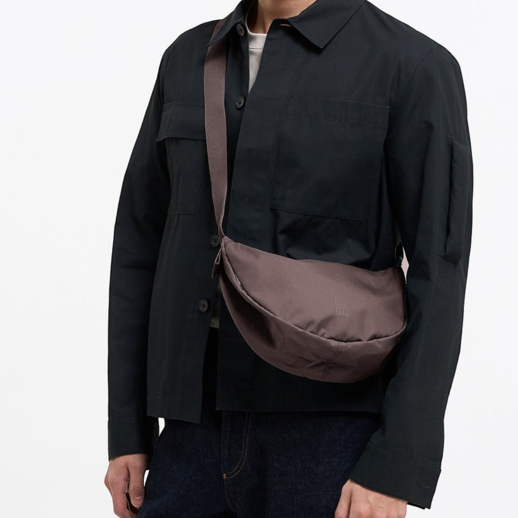 Lieblingstasche Moon Bag Small in dark brown worn as a crossbody bag by a man in a black jacket