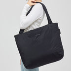 Lieblingstasche Norva 2in1 black padded shopper bag carried over the shoulder by a woman in a white long-sleeve top