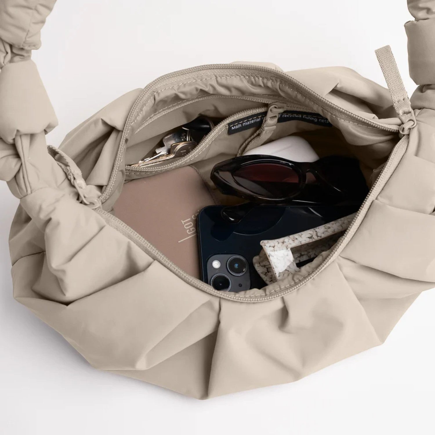 Lieblingstasche GOT BAG Pleat Moon Bag Small in beige, showing the spacious interior with zipper and organized items.