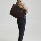 A woman carrying a dark brown suede Lieblingstasche Pretty Wonder Suede tote bag over her shoulder.