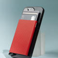 Lieblingstasche red fluted MagSafe card protector attached to the back of a black smartphone with credit cards inside.