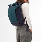 Lieblingstasche Roll Pack 2.0 backpack in dark green and navy blue worn by a woman against a white background