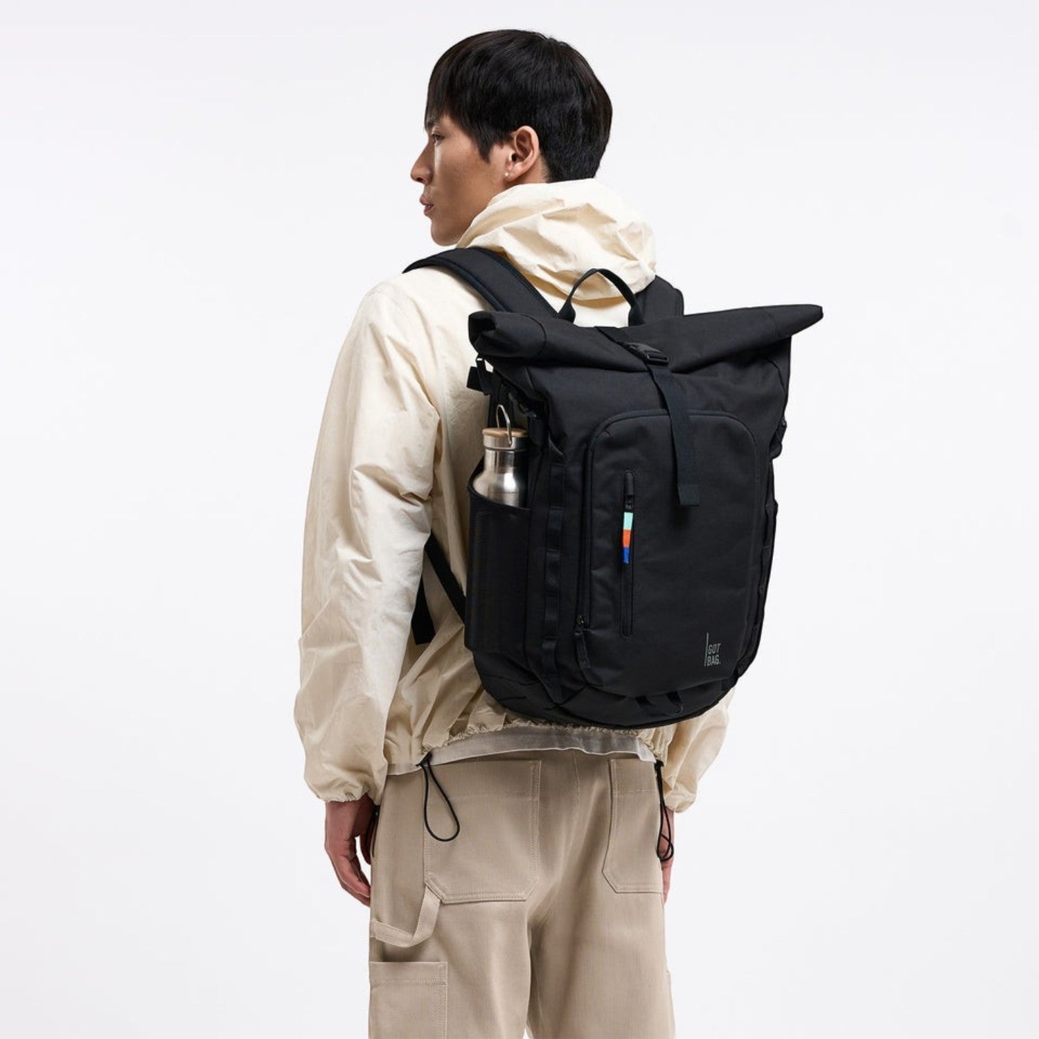 Lieblingstasche Rolltop Adventure black backpack with water bottle in side pocket and colorful stripe detail.