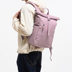 Lieblingstasche Rolltop Easy Small lilac backpack with front zip pocket and side pocket, worn by a person.