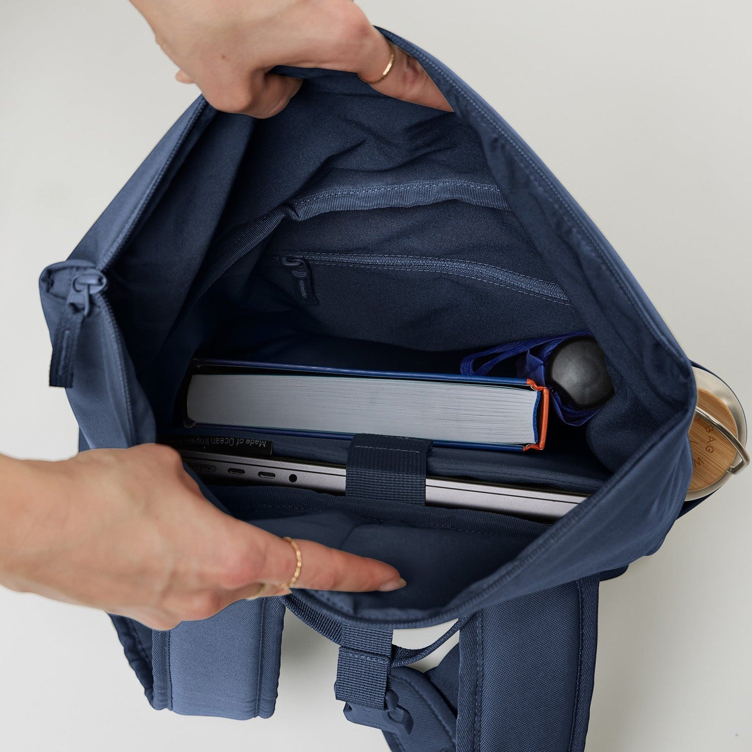 Lieblingstasche Rolltop Easy Small backpack in navy blue canvas, showing interior with laptop, book, and water bottle.