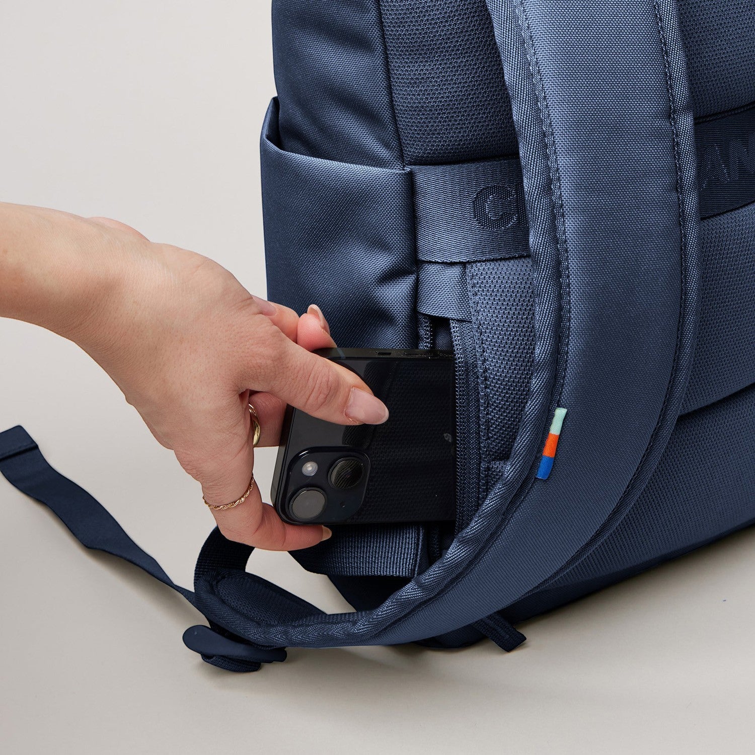 Lieblingstasche Rolltop Easy Small navy blue backpack with a side pocket holding a smartphone.