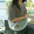 Lieblingstasche Roop L crossbody bag in sage green and white canvas with red accent stripe worn by a woman