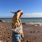 Lieblingstasche Roop moonbag made from recycled white sailcloth worn by a woman on a sunny beach