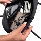 Lieblingstasche Strike Bag Small in black, showing the interior filled with a phone, wallet, keys, and hair clip.