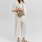 Woman wearing a cream linen outfit and carrying a taupe Lieblingstasche Style Mate crossbody bag