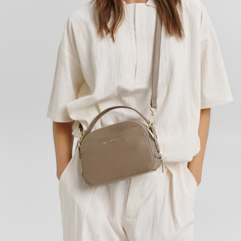 Lieblingstasche Style Mate taupe leather crossbody bag with top handle worn by a woman in a cream outfit