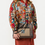 Lieblingstasche shoulder bag with textured brown fabric and a small cat logo patch held by a model in a floral jacket
