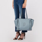 Lieblingstasche Tote L in light blue leather with side tie details held by a woman in jeans and black heels