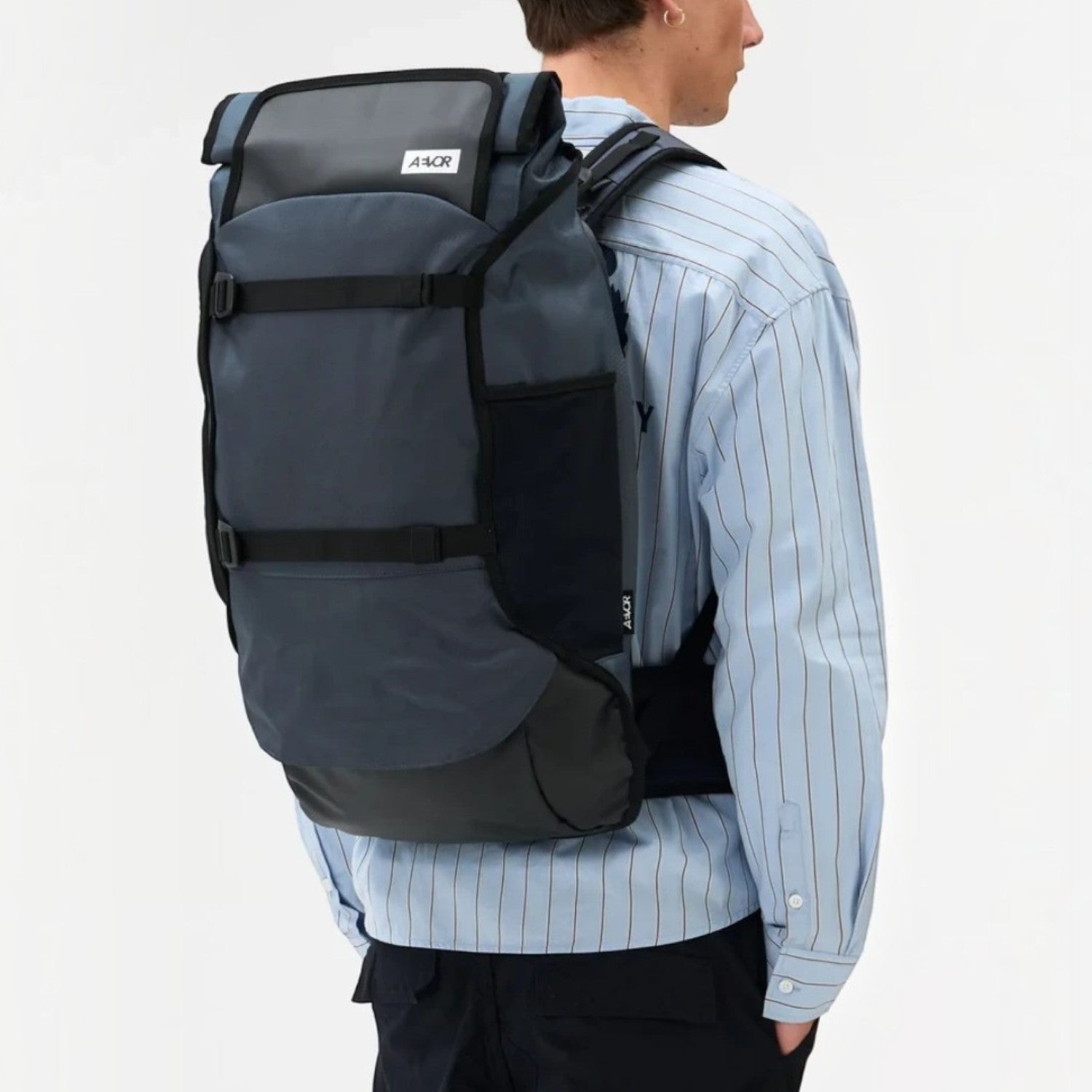 Lieblingstasche Travel Pack in dark grey with rolltop design, worn by a man against a white background.