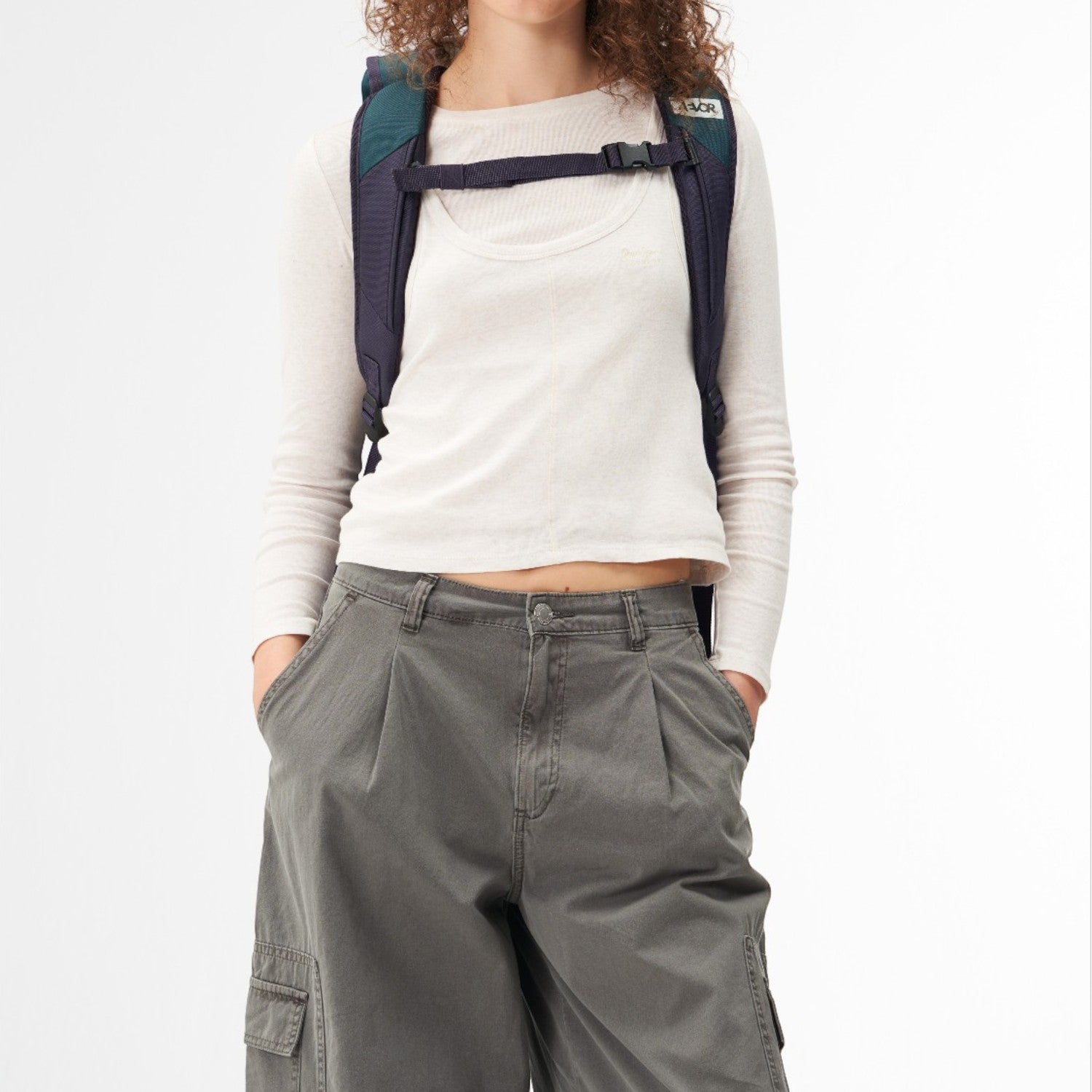 A model wearing a Lieblingstasche Trip Pack backpack with navy and teal straps against a white background