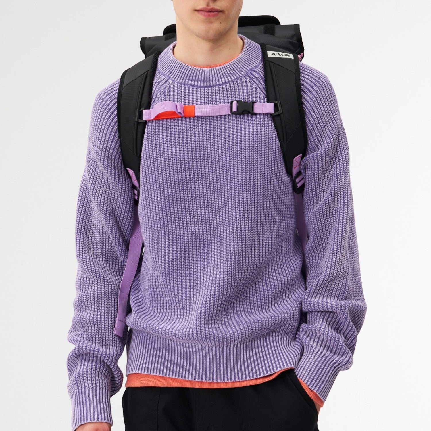 Lieblingstasche Trip Pack black backpack with purple straps worn by a man in a lavender sweater