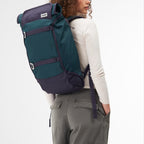 Lieblingstasche Trip Pack backpack in teal and dark purple worn by a woman against a white background