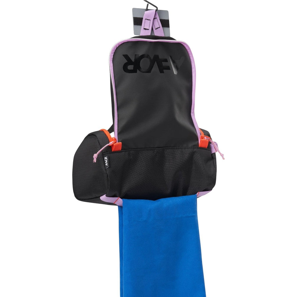Lieblingstasche Wash Pack hanging open with black fabric, purple trim, orange accents, and a blue towel inside.